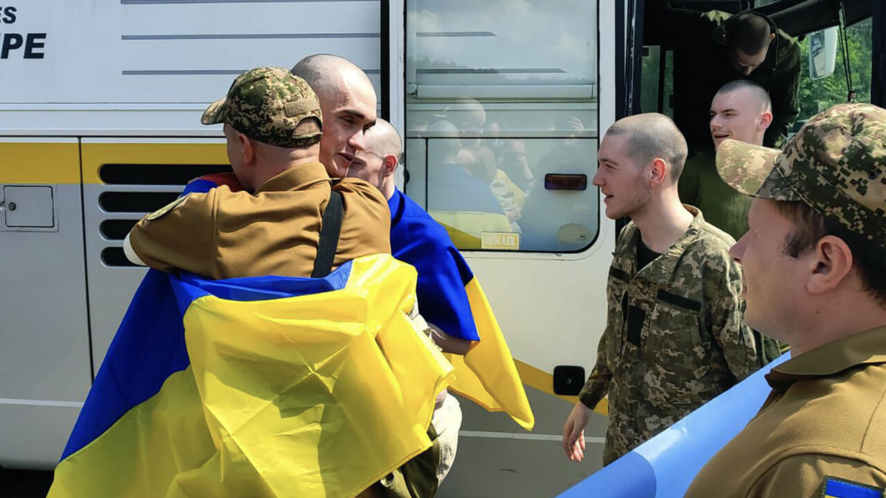Des prisonniers de guerre ukrainiens enveloppés dans des drapeaux nationaux ukrainiens réagissent à la suite d'un échange dans un lieu non divulgué, le 9 juin 2025.