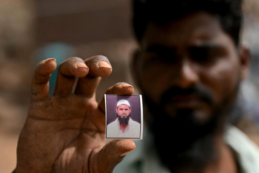 Cheikh Imran montre une photo de son frère Cheikh Latif Sheru, un agriculteur qui s'est suicidé en raison de l'accumulation de prêts financiers, sur leurs terres agricoles dans le village de Mochi Pimpalgaon, dans l'Etat du Maharashtra, le 3 mai 2025 en Inde