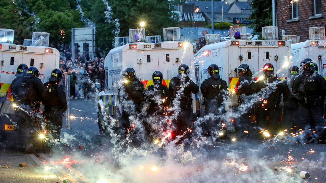 Des feux d'artifice lancés sur la police anti-émeute lors d'une troisième nuit de manifestations visant les immigrés à Ballymena, en Irlande du Nord, le 11 juin 2025.