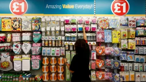 Une femme devant un étalage de produits chez Poundland.