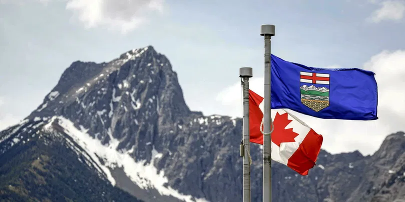 Les drapeaux du Canada et de l’Alberta flottent au vent, avec le mont Wedge en arrière-plan, sur le site de la réunion des dirigeants du G7 à Kananaskis, en Alberta, juin 2025.