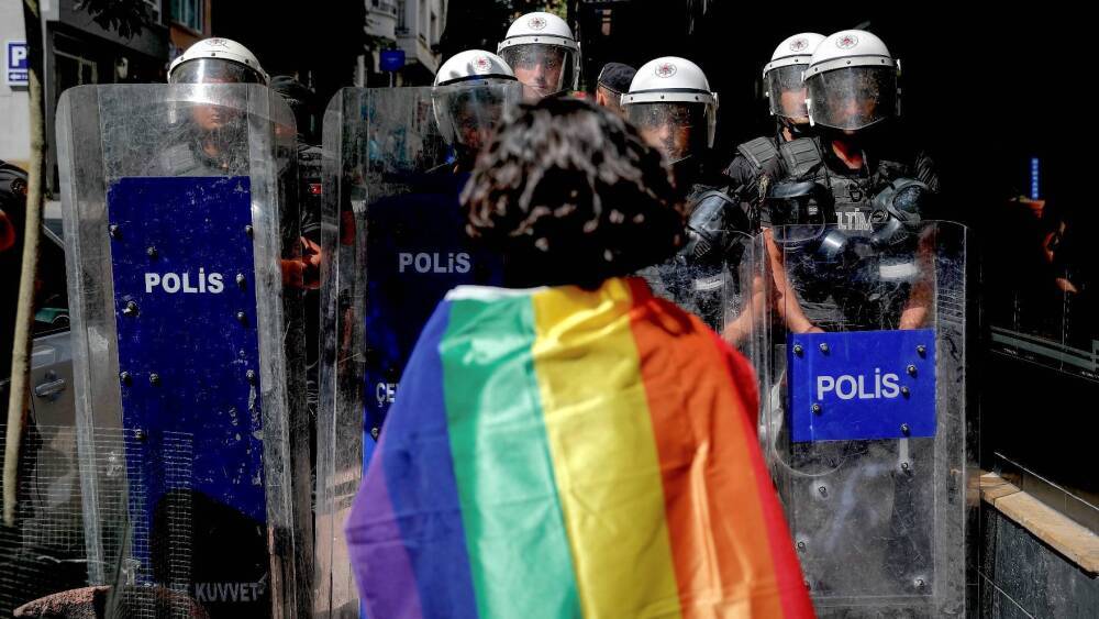 Participant à la marche des fiertés face à des policiers à Istanbul en 2022