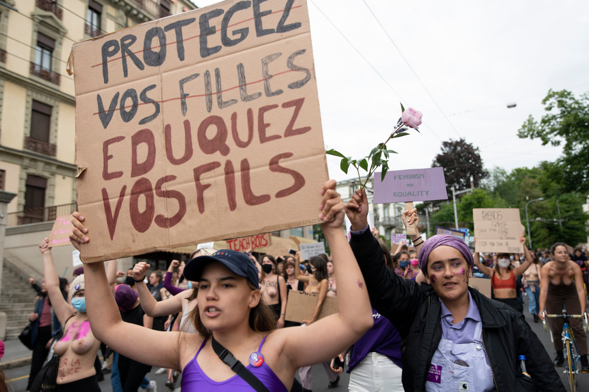 Manifestantes lors de la Grève féministe à Lausanne, portant des pancartes avec des messages de protection et d’égalité.