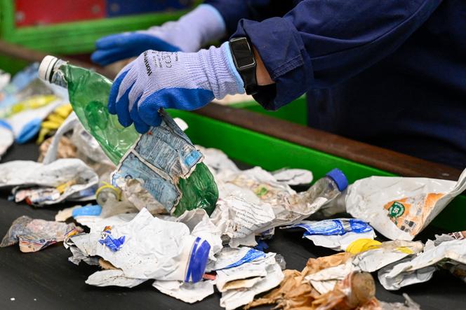 Contrôle manuel des divers emballages écrasés et transportés sur un tapis roulant dans le centre de déchets plastique « surtri » à Epinal, le 28 juin 2024.