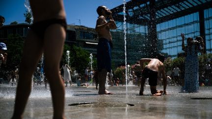 Des personnes se rafraîchissent dans une fontaine du parc André-Citroën alors qu'une vague de chaleur frappe l'Europe, le 29 juin 2025, à Paris. (JULIE SEBADELHA / AFP)