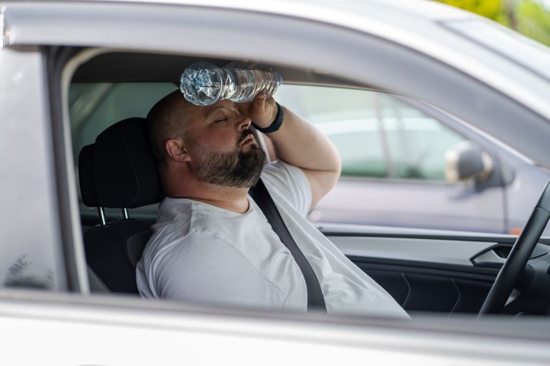 Homme en surpoids conduisant une voiture avec climatisation défectueuse par temps chaud d'été