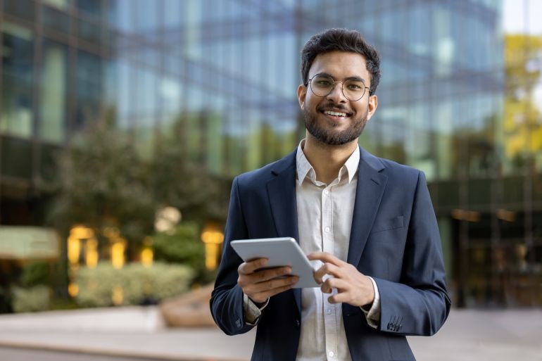 Jeune entrepreneur utilisant une tablette devant un bâtiment moderne
