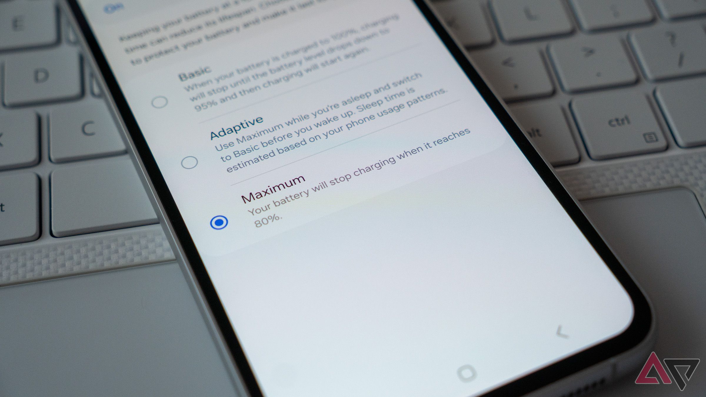Un téléphone sur un clavier d'ordinateur portable affichant le paramètre de limite de charge de 80 %