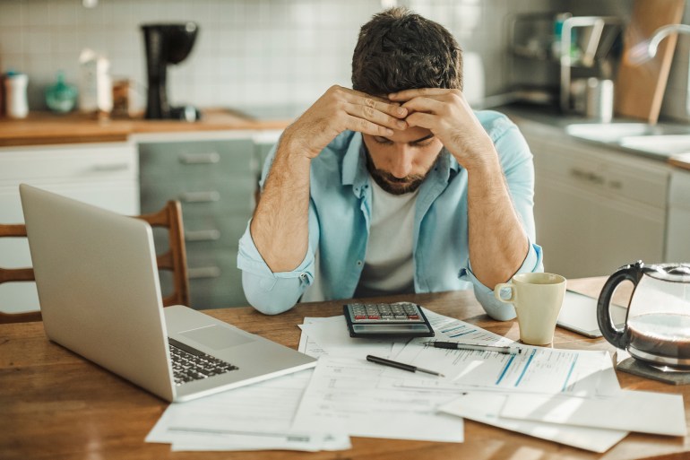 Jeune homme stressé gérant ses dettes dans la cuisine