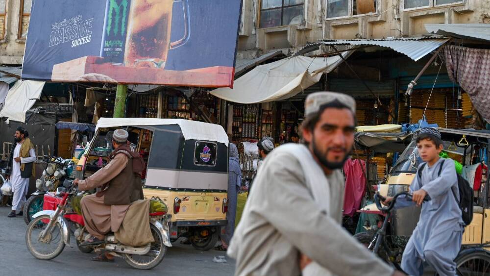Hommes afghans passant devant un panneau publicitaire en Iran