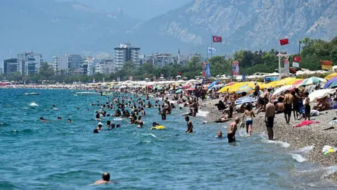 Plage en Turquie avec des gens se baignant sous des parasols