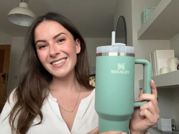 Femme tenant une gourde Stanley teal avec une paille.