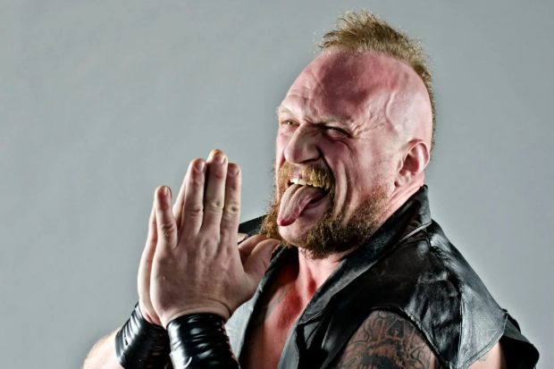 Kevin Nikel, lutteur WWE, en pose avec un mohawk et des tatouages.