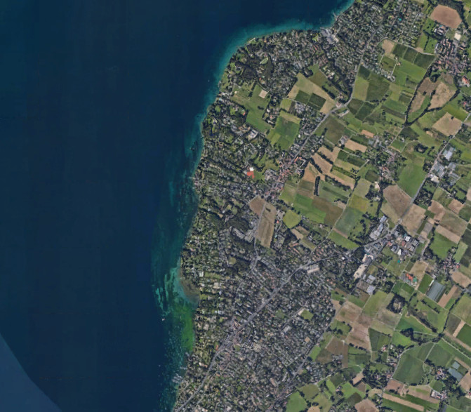 Vue satellite montrant des terres agricoles et des zones résidentielles près d’un grand lac.