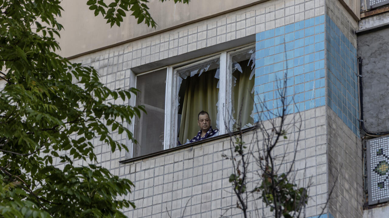 Un homme regarde par la fenêtre brisée d'un appartement suite à une attaque russe à Odessa, en Ukraine, le 19 juillet 2025.
