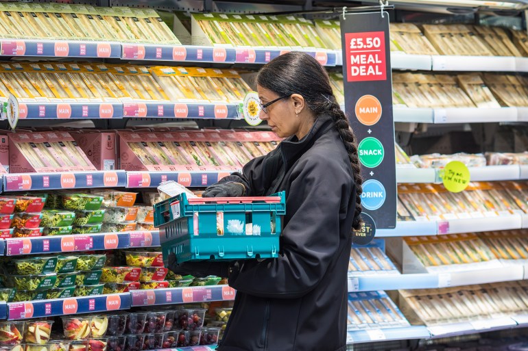 Employée réapprovisionnant les rayons d'un supermarché Marks and Spencer à Londres