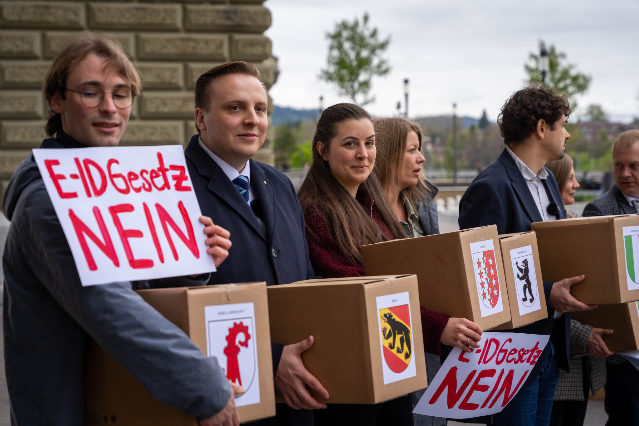 Personnes remettant des boîtes de pétitions marquées ’E-ID Gesetz Nein’ devant le Bundeshaus à Berne.