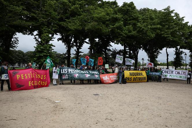 Des manifestants brandissent des pancartes lors d’un rassemblement contre la loi Duplomb, près de l’Assemblée nationale, à Paris, le 27 mai 2025.