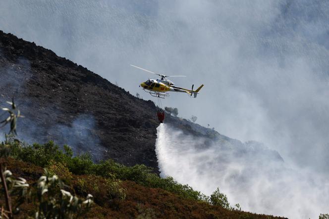 Un hélicoptère déverse de l’eau alors que les efforts pour lutter contre un incendie de forêt se poursuivent dans la région d’Arouca, au Portugal, le 30 juillet 2025.