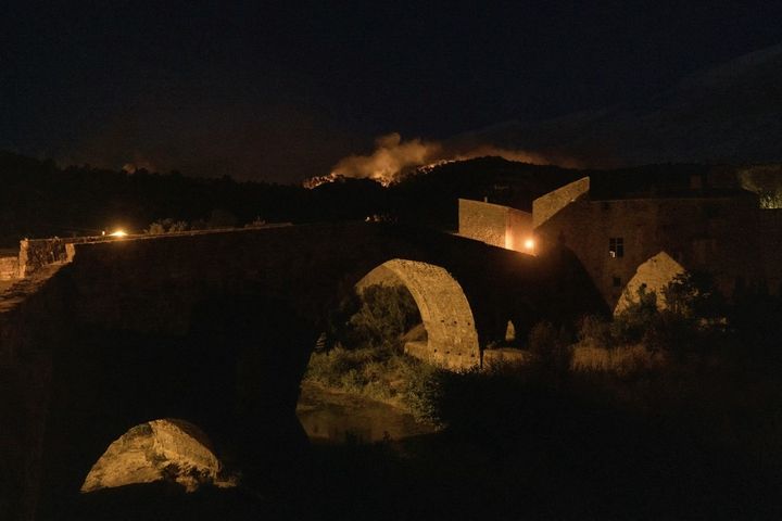 Des volutes de fumée provenant d'un incendie dans l'Aude sont visibles au-dessus du vieux pont de Lagrasse.