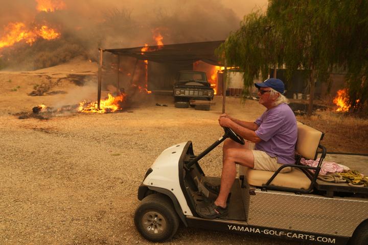 Un habitant évacue sa propriété atteinte par l’incendie, à Hasley Canyon (Californie), le 7 août 2025.