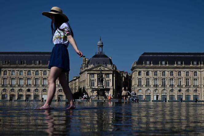 Une femme se rafraîchit dans le « Miroir d’Eau » à Bordeaux, le 8 août 2025, alors qu’une vague de chaleur s’étend sur le sud du pays.
