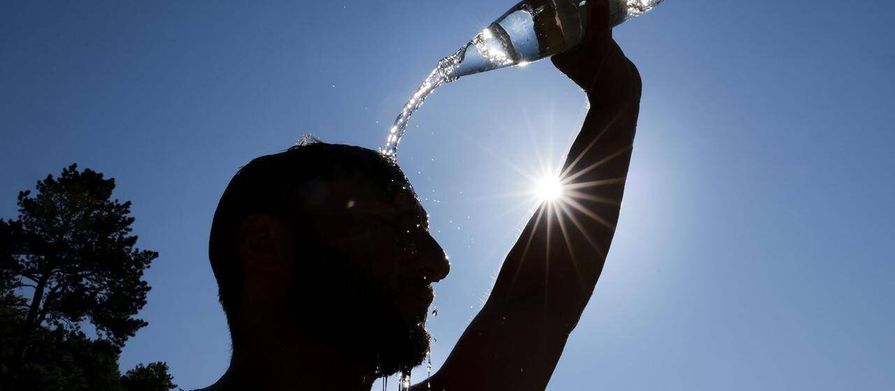 Homme se rafraîchant en versant de l’eau sur le front
