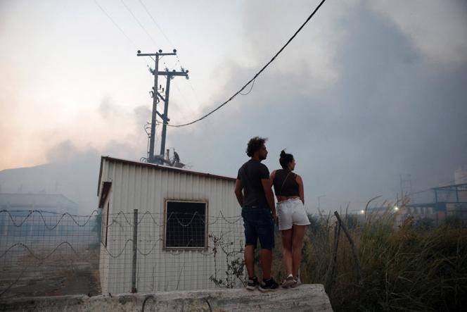 Des personnes observent un incendie de forêt à Sichaina, près de Patras, en Grèce, le 13 août 2025.