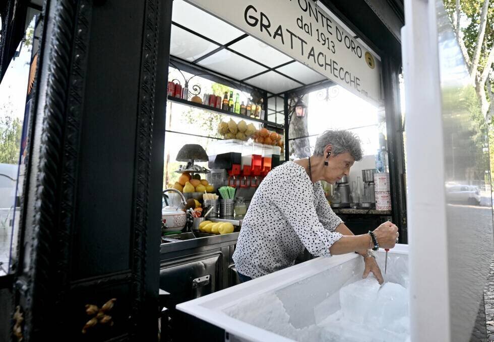 La propriétaire du kiosque « Alla Fonte d'Oro » casse des blocs de glace pour préparer de la « Grattachecca » à Rome