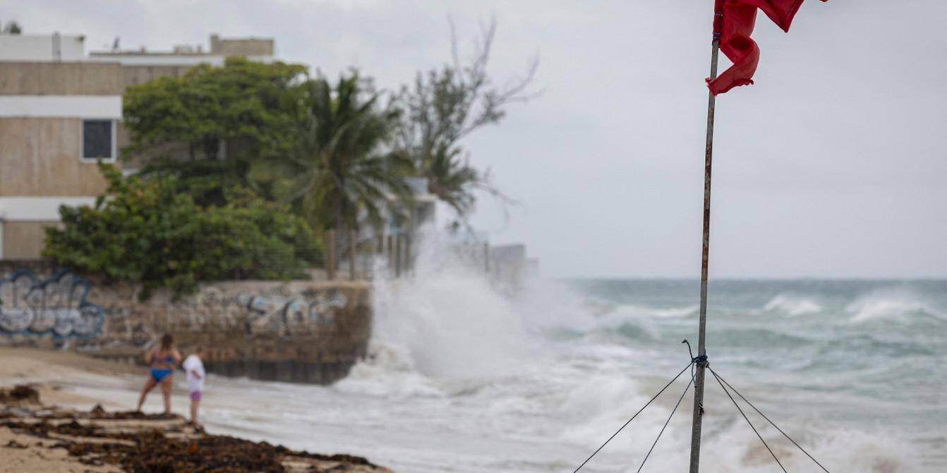 Surfeurs et plage sous le ciel couvert avant Erin