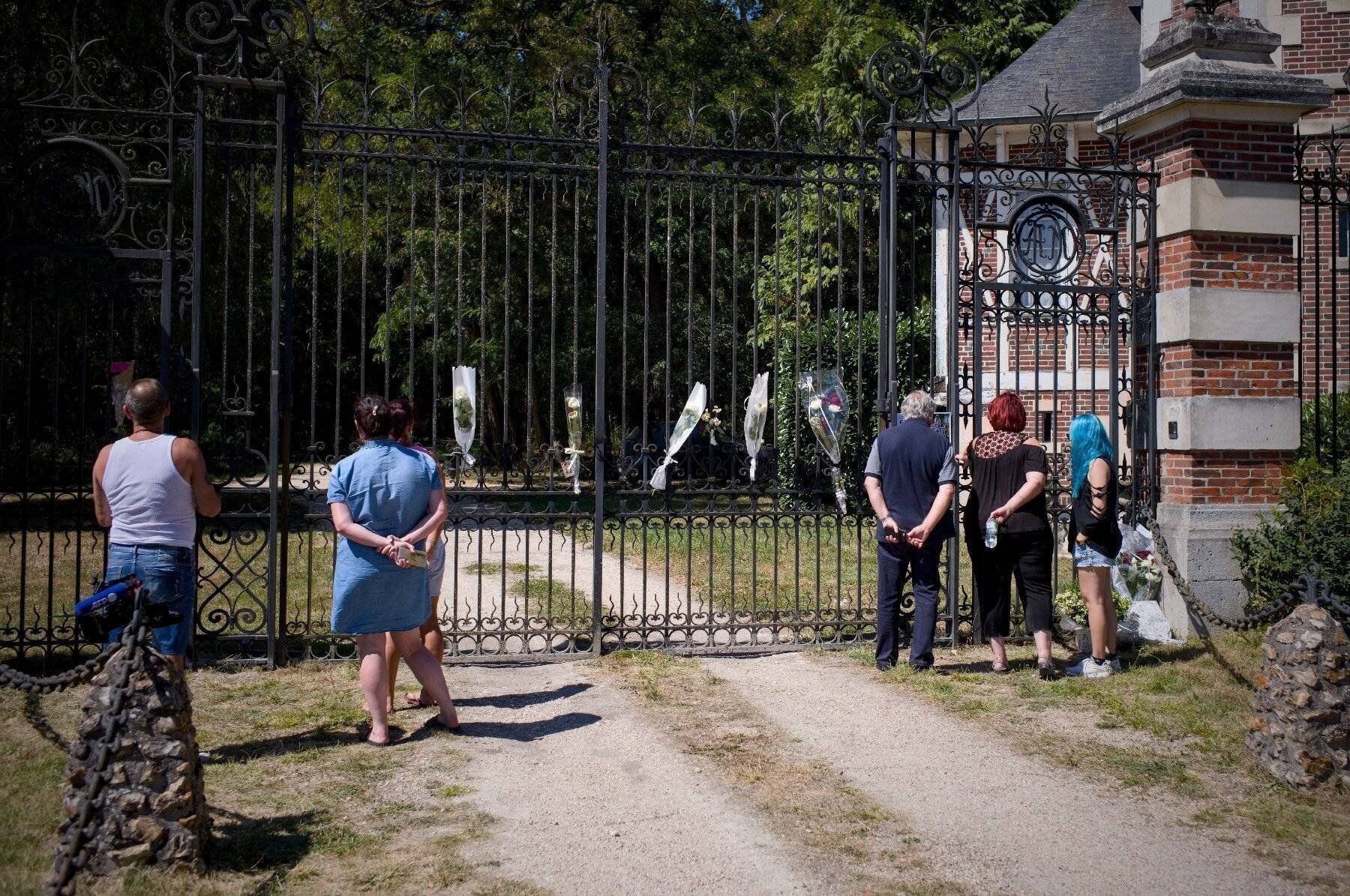 Des spectateurs autour d'une plaque en hommage à Delon