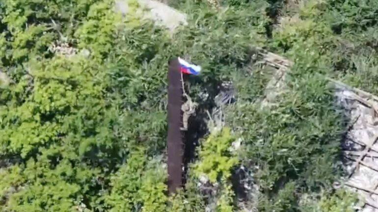 Soldat russe levant un drapeau après la prise d'une zone dans le Donetsk