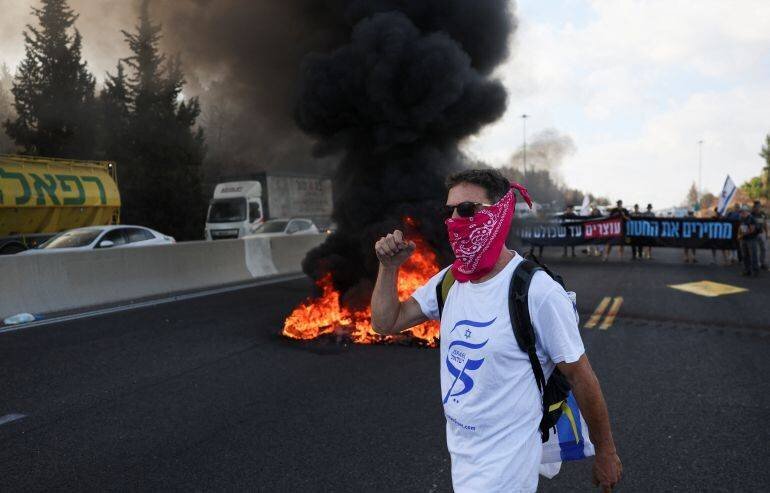 Jeune allume des pneus pour bloquer une rue en Israël lors des manifestations