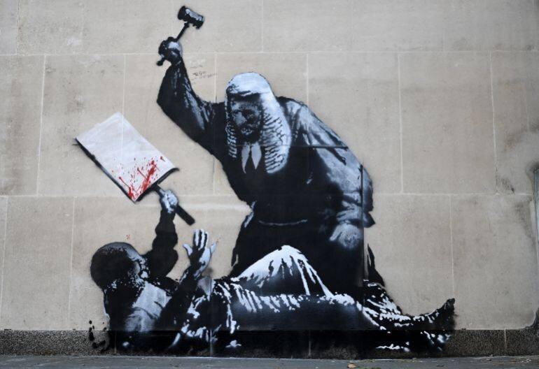 Fresque attribuée à Banksy sur la Royal Courts of Justice à Londres, représentant un manifestant et un juge