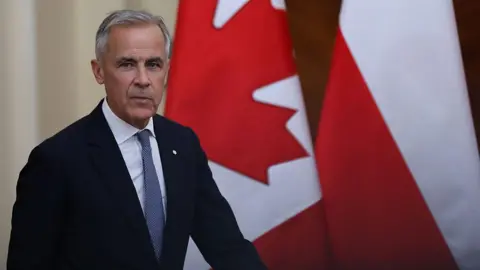Mark Carney marche devant deux drapeaux canadiens