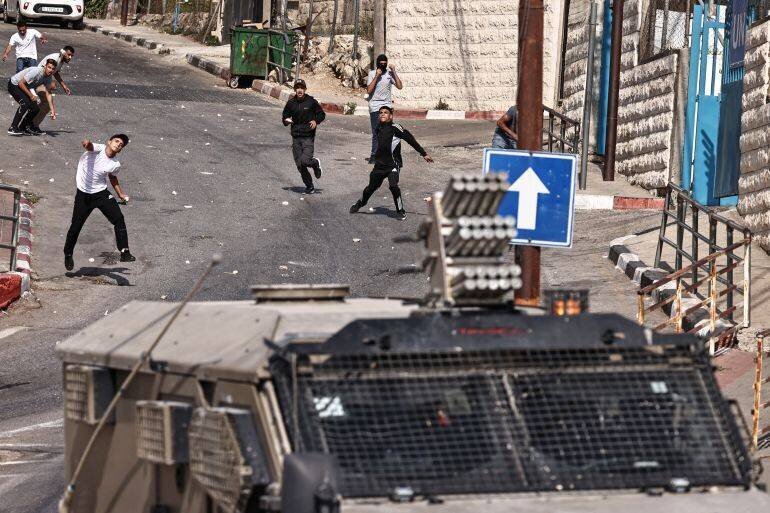 Jeunes palestiniens jettent des pierres sur des soldats israéliens lors d'une rafle à Ramallah