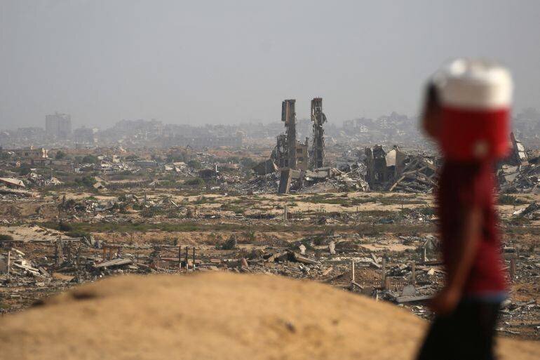 Enfant palestinien transportant un bidon d'eau devant les ruines du camp de Nuseirat