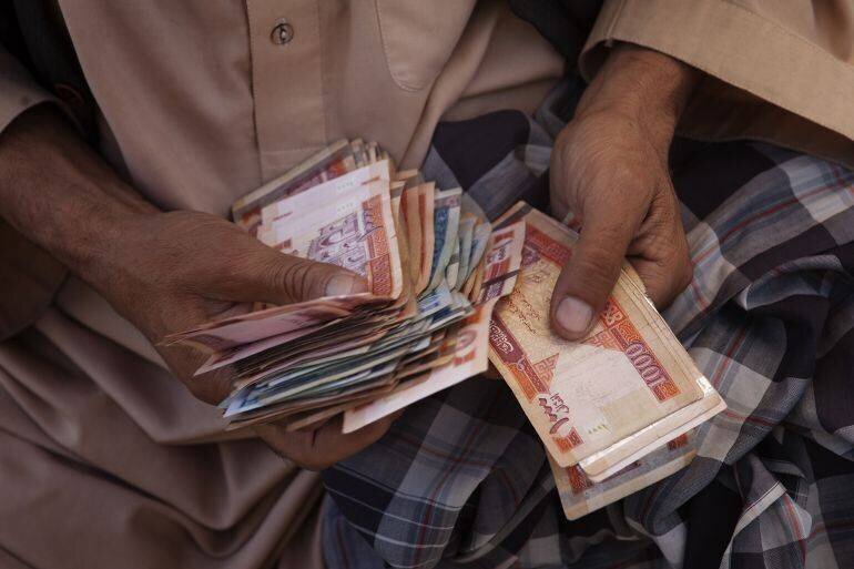 Changeur de monnaie comptant des billets afghans dans la rue