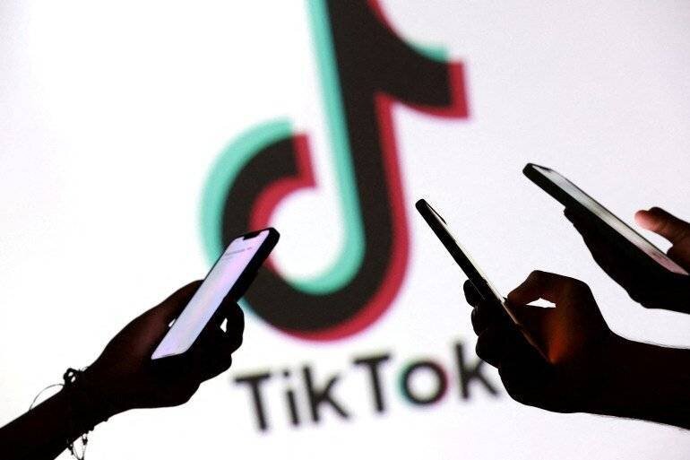 Adolescents tenant des smartphones devant le logo TikTok