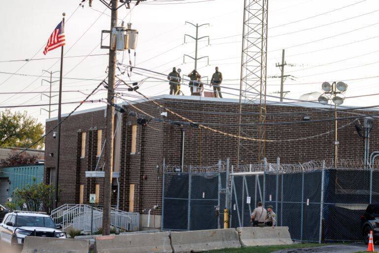 Agents masqués d'ICE observent la foule depuis le toit d'un centre de détention près de Chicago