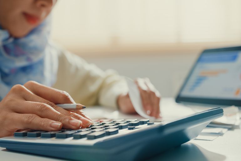 Closeup Asian muslim woman with hijab using tablet calculator.
