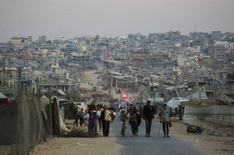 Des Palestiniens marchent près de bâtiments détruits à Khan Younis, sud de la bande de Gaza, le 25 octobre 2025.