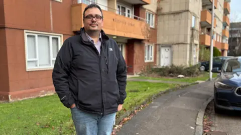 Dimitrios Kampouris devant l'entrée de Westfield Court