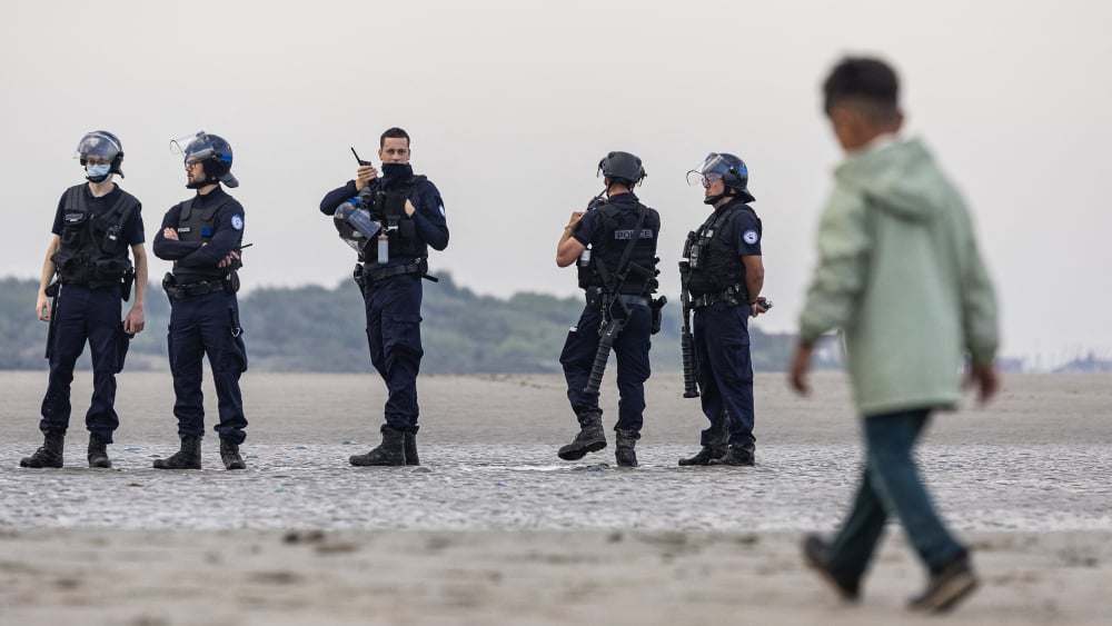 Agents de police et migrants près du littoral